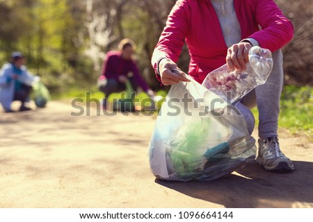 Improving environment. Kind eco-friendly volunteers holding packets and gathering garbage Royalty-Free Stock Photo #1096664144