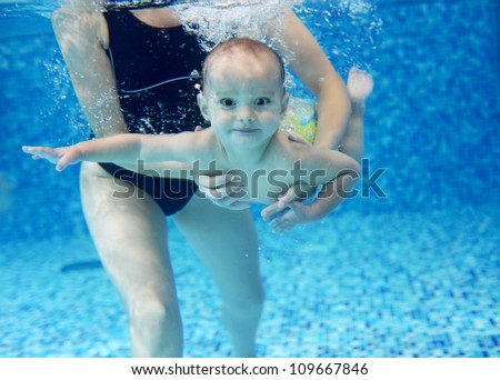 Little boy learning to swim in a swimming pool, mother holding the child
