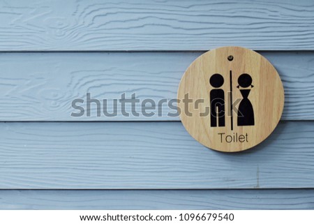 Wooden toilet sign hanging on the blue wood wall