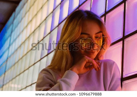 Beautiful girl with mysteriously looking in front of colourful neon background 