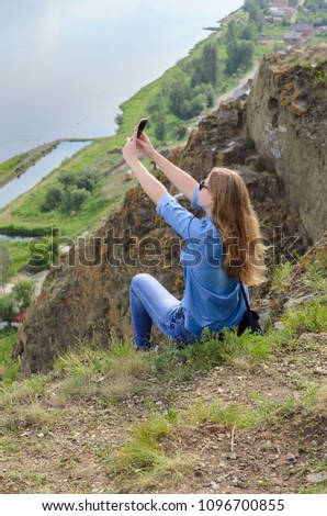 Young girl in blue clothes, wearing sunglasses doing selfie in summer outdoors