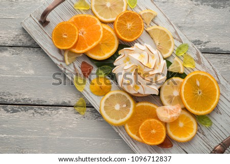 Bright photo of lemon tart and different citrus fruits over wooden background