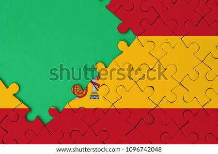 Spain flag  is depicted on a completed jigsaw puzzle with free green copy space on the left side.