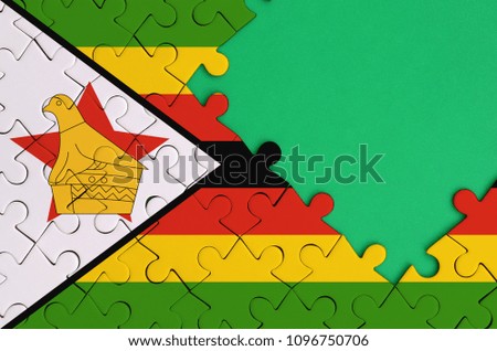 Zimbabwe flag  is depicted on a completed jigsaw puzzle with free green copy space on the right side.