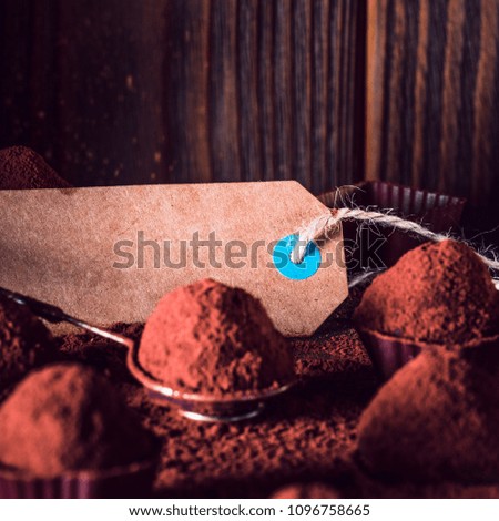 Chocolate truffles and sale tag, macro. delicious homemade truffle with dark chocolate and cocoa powder. Gourmet candies made by chocolatier on spiral dipping tool. Sweet dessert. Chocolaterie border
