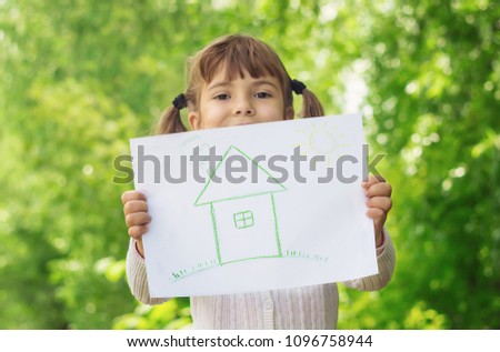 Drawing of a green house in the hands of a child. Selective focus. 