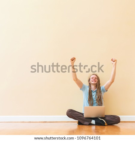 Happy successful man using his laptop in a big room
