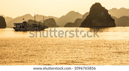 Ha long bay islands, tourist  boats and seascape in the evening with golden light reflection on water, Ha Long, Vietnam.