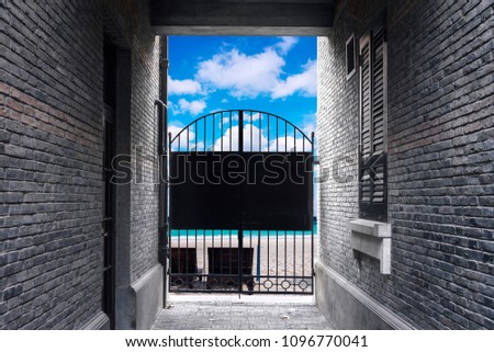 Brick Wall and black steel door close, Blocking freedom chance to outside, beach and blue sky sea and blue sky background.