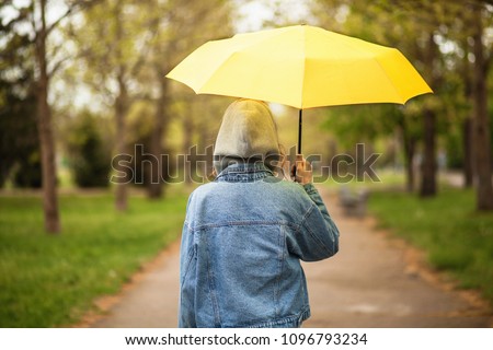 Outoor picture of a young woman with yellow umbrella
