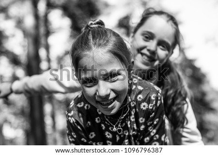 Two girls sisters or girlfriends having fun outdoors. Black and white photo.