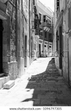 Typical narrow street on the island of Malta. Buildings with traditional colorful maltese balconies in historical part of Valletta. Black and white picture