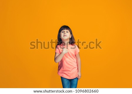 Choose me. Happy teen girl standing, smiling, pointing to himselth isolated on trendy orange studio background. Beautiful female half-length portrait. Human emotions, facial expression concept.