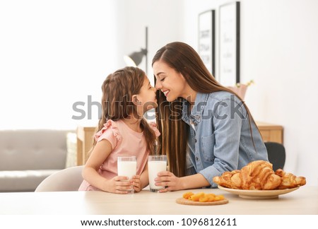 Mother and daughter having breakfast with milk at table Royalty-Free Stock Photo #1096812611