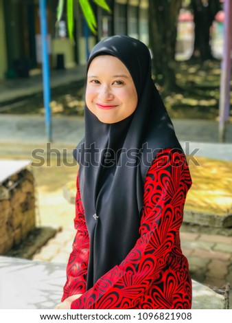 Portrait of beautiful young Asian Muslim woman wearing Baju Kurung and hijab posed under a bamboo tree. 