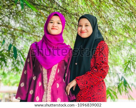 Young beautiful Muslim women in a headscarf with Baju Kurung and Baju Kebaya posing under bamboo tree.  