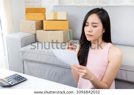 Young Asian woman entrepreneur or freelance online seller working at home checking orders preparing for delivery packages to customers