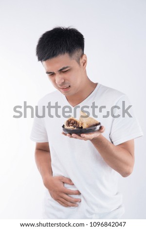 A man has a stomachache after eating too much delicious zongzi(rice dumpling) on Dragon Boat Festival, Asian traditional food, white background