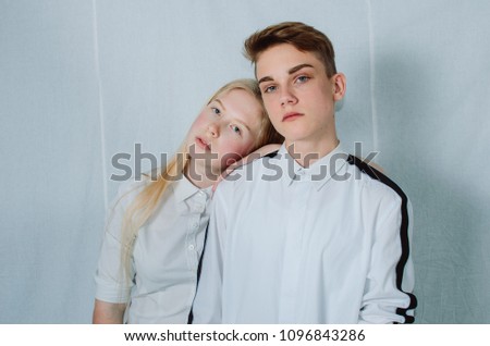 Teenagers , brother and sister. The relationship between people in the family . Dressed in a white shirt and jeans. Girl blonde long hair guy model.