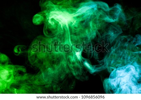 Thick colorful smoke of green and blue  on a black isolated background. Background from the smoke of vape