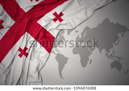 waving colorful national flag of georgia on a gray world map background.