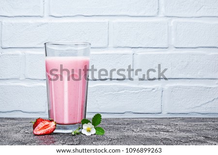 Healthy breakfast. Glass of homemade yogurt and fresh strawberries with spring flowers on gray concrete background