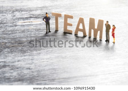 TEAM word made from colored wooden letters on wood with miniature business people