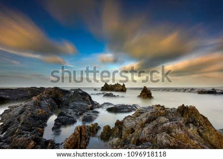 Long exposure seascape and rocky beach during sunset . Nature composition. A slow shutter speed was used to see the movement .Soft and grain effect.