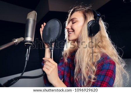 Play on! Gorgeous good-looking female vocal artist singing in the modern recording studio in order to create new album.  