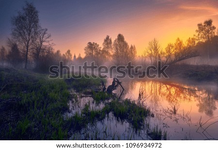 A small river in the early May morning with a church in the distance on its coast