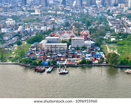 Beautiful scenery, many colorful houses and green trees are lacated along riverside Chao Praya River. Temple , boats and other buildings are far away in colorful ,green trees and river backgrounds