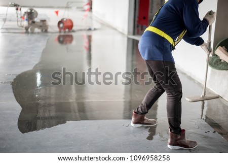 Construction worker painting epoxy flooring or floor hardener Royalty-Free Stock Photo #1096958258