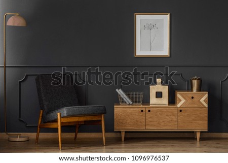Dark, retro living room interior concept with black chair, lamp, poster, cabinet and wooden floor