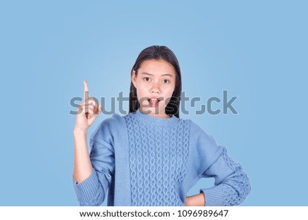 Portrait of young girl pointing finger up isolated on blue background