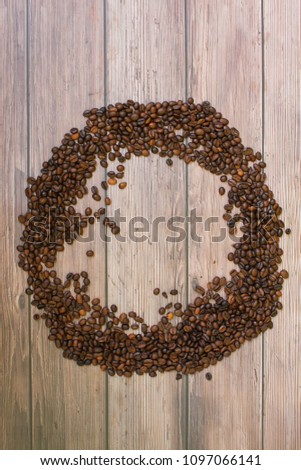 Coffee beans scattered on wood background in circle top view with plase for text
