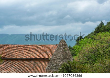 Tiled roof of an old building on a background of cloudy mountains.