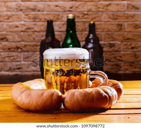 A mug of beer and smoked sausage on the table Beer bottles in the background.