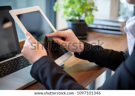 Business woman on office table and woman working in the background.