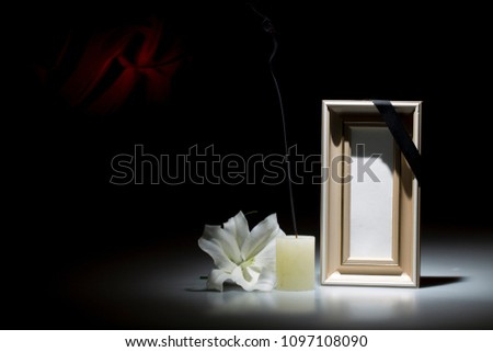 Blank wooden  frame, with smoky candle and white lily flower on dark background with red decoration