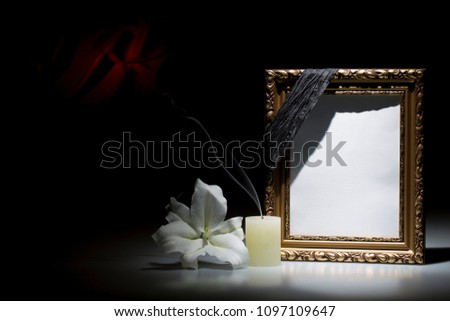Blank rustic golden picture  frame, with smoky candle and white lily flower on dark background with red decoration