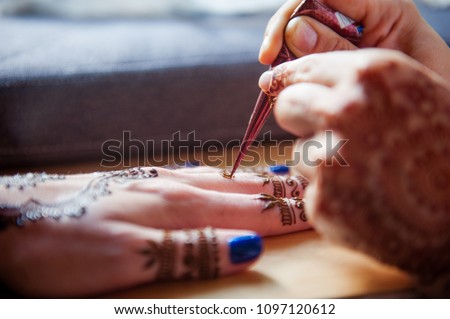 Drawing mehndi on the hand of a girl