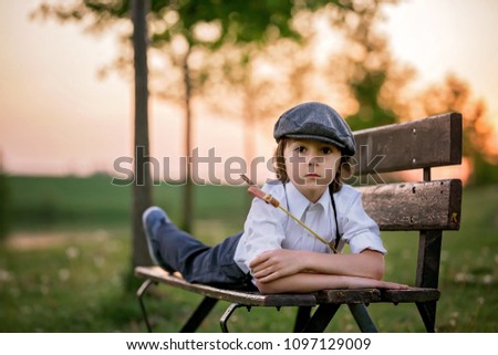 Portrait of child playing with bow and arrows, archery shoots a bow at the target on sunset Royalty-Free Stock Photo #1097129009