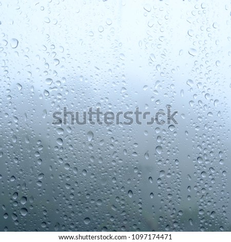 Rain drops on window glasses surface with cloudy and green background . Natural Pattern of raindrops isolated on cloudy background.