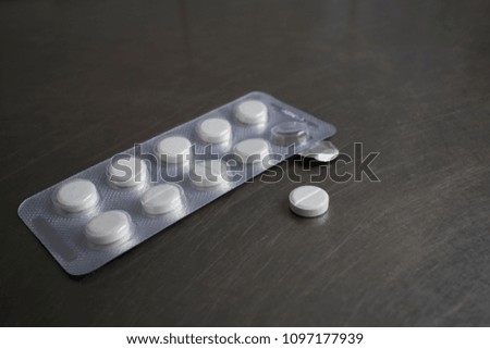 medical tablets in a package and one tablet on the medical table