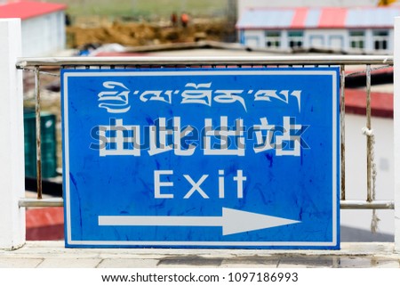Travel - Exit sign with arrow point to the right ( English, Chinese, Tibetan) on a railway platform, view from the QINGHAI TIBET RAILWAY on the direction toward Lhasa, China.