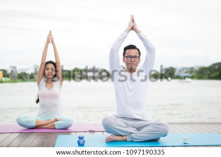 man and woman practicing yoga and meditation on mat near lagoon. health concept.