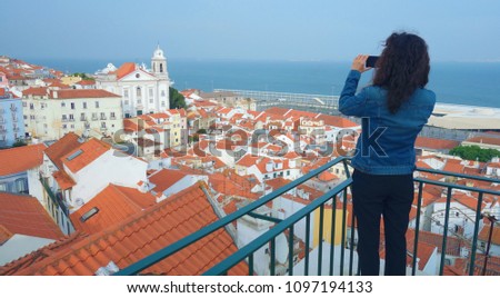 Girl taking a photo from Santa Luzia viewpoint. Lisbon, Portugal town skyline at Alfama.             