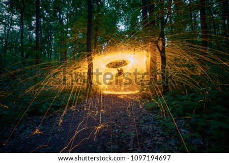 Burning steel wool spinned in the forest. Showers of glowing sparks from spinning steel wool