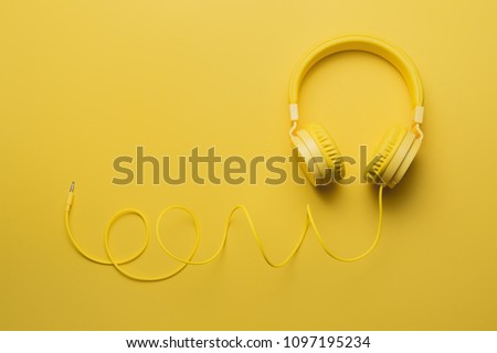 Yellow headphones on yellow background. Music concept.