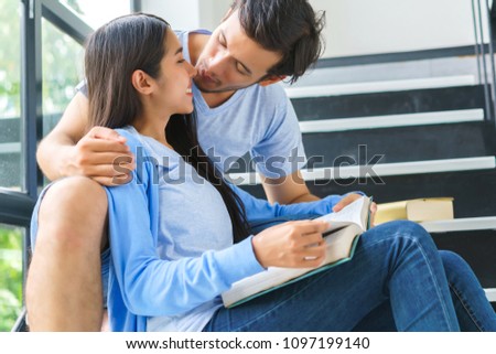 Students man and woman posing looking book indoors in an university campus.
